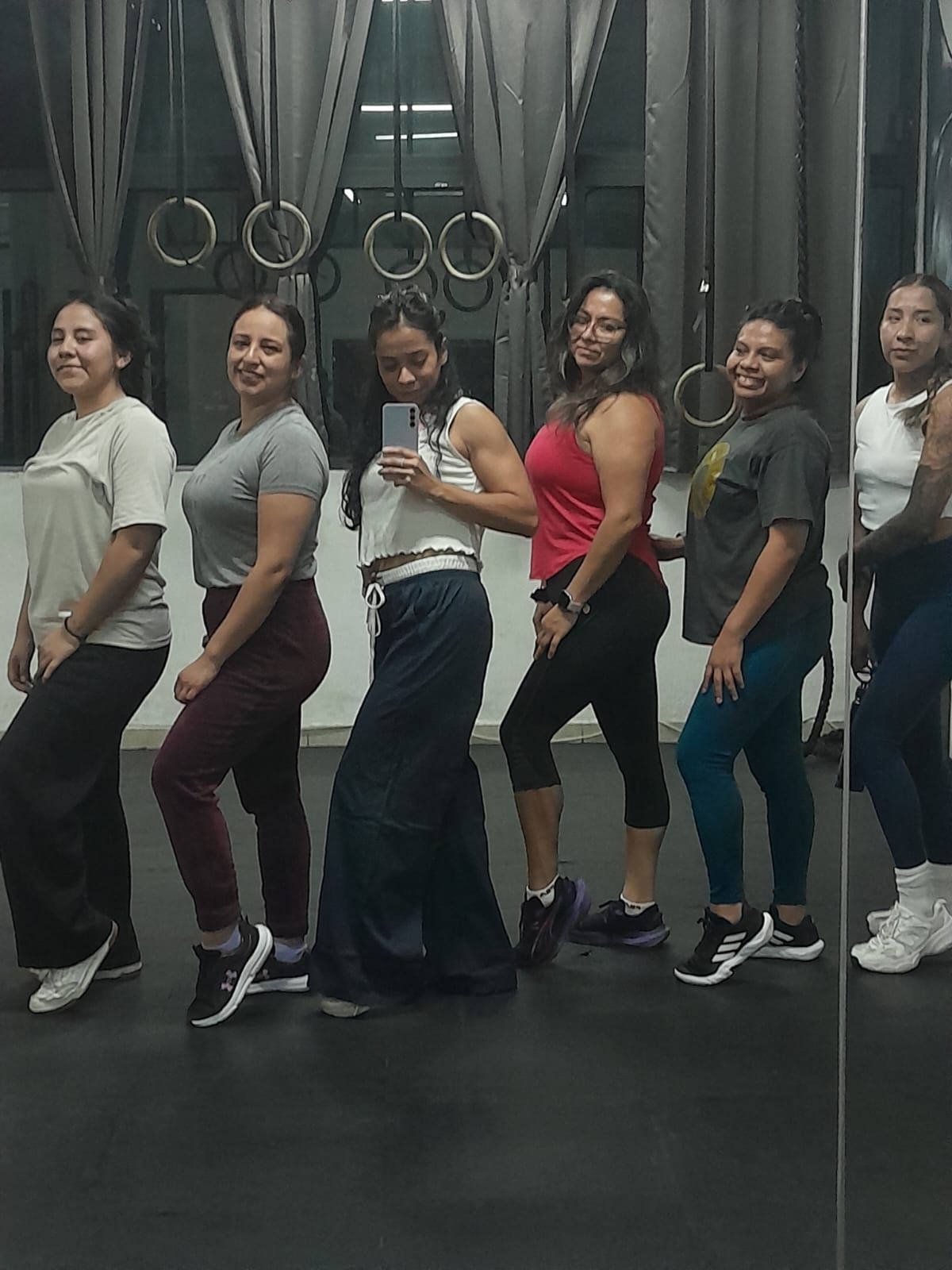Grupo de alumnas de la clase de fuerza posando en el salón de fitness